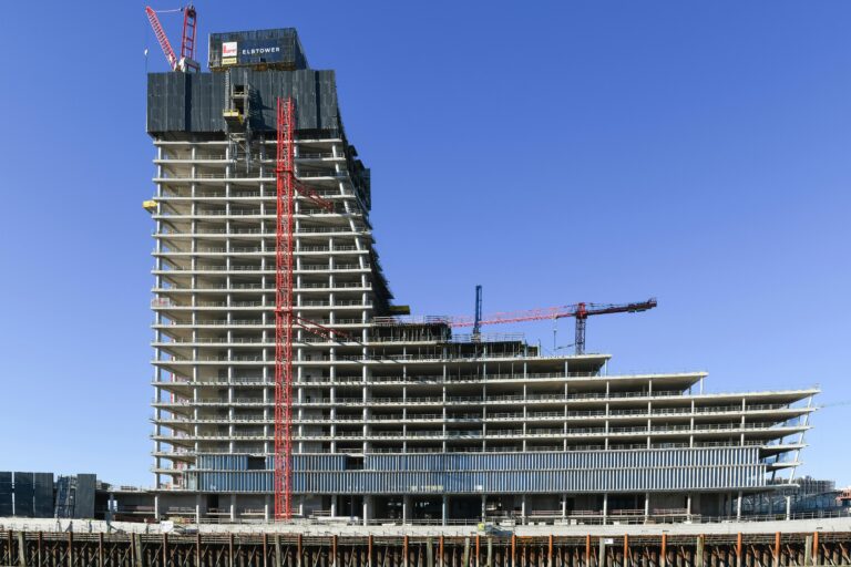 Aerial view of a modern high-rise under construction in Hamburg, featuring cranes and concrete structures.